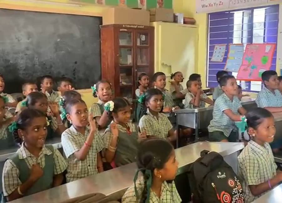 Children in a classroom raising their hands