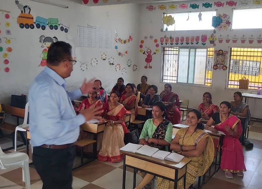 Trainer speaking to a room of teachers seated at desks