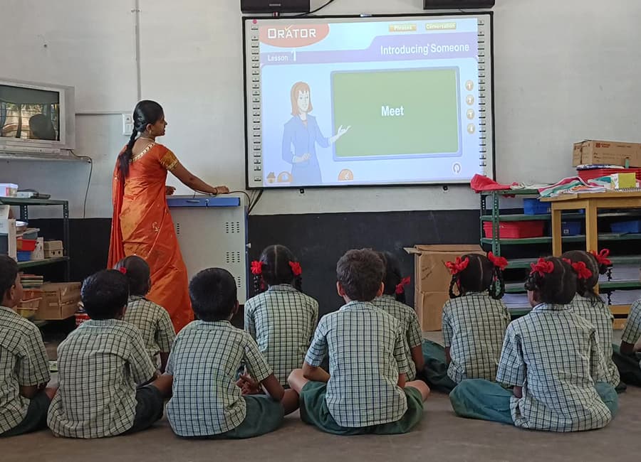Teacher leading a lesson from a projected screen as children sit on the floor
