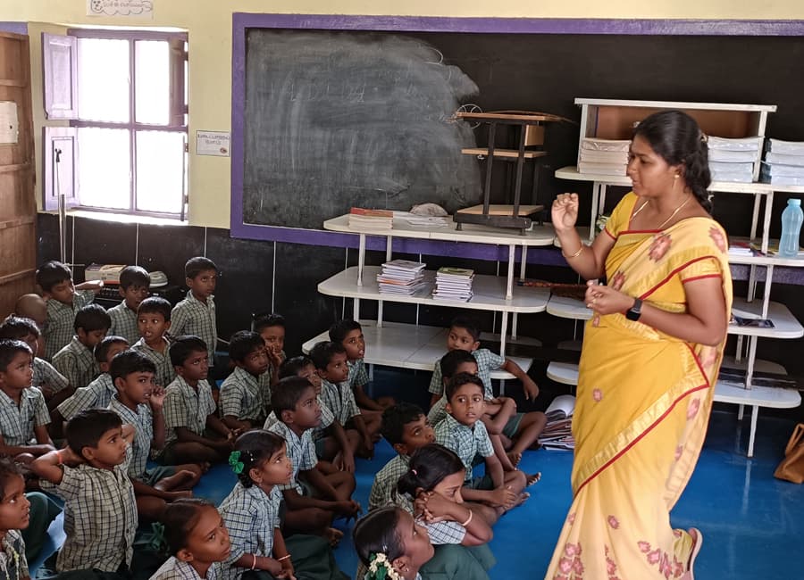 Teacher addressing a full classroom of seated children