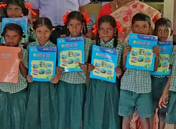 Schoolchildren in uniform holding up their MiKids English books
